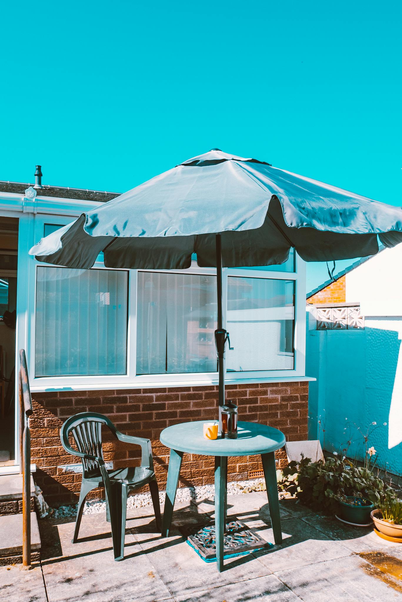 Bright patio setup with table, chairs, and an umbrella under clear skies.